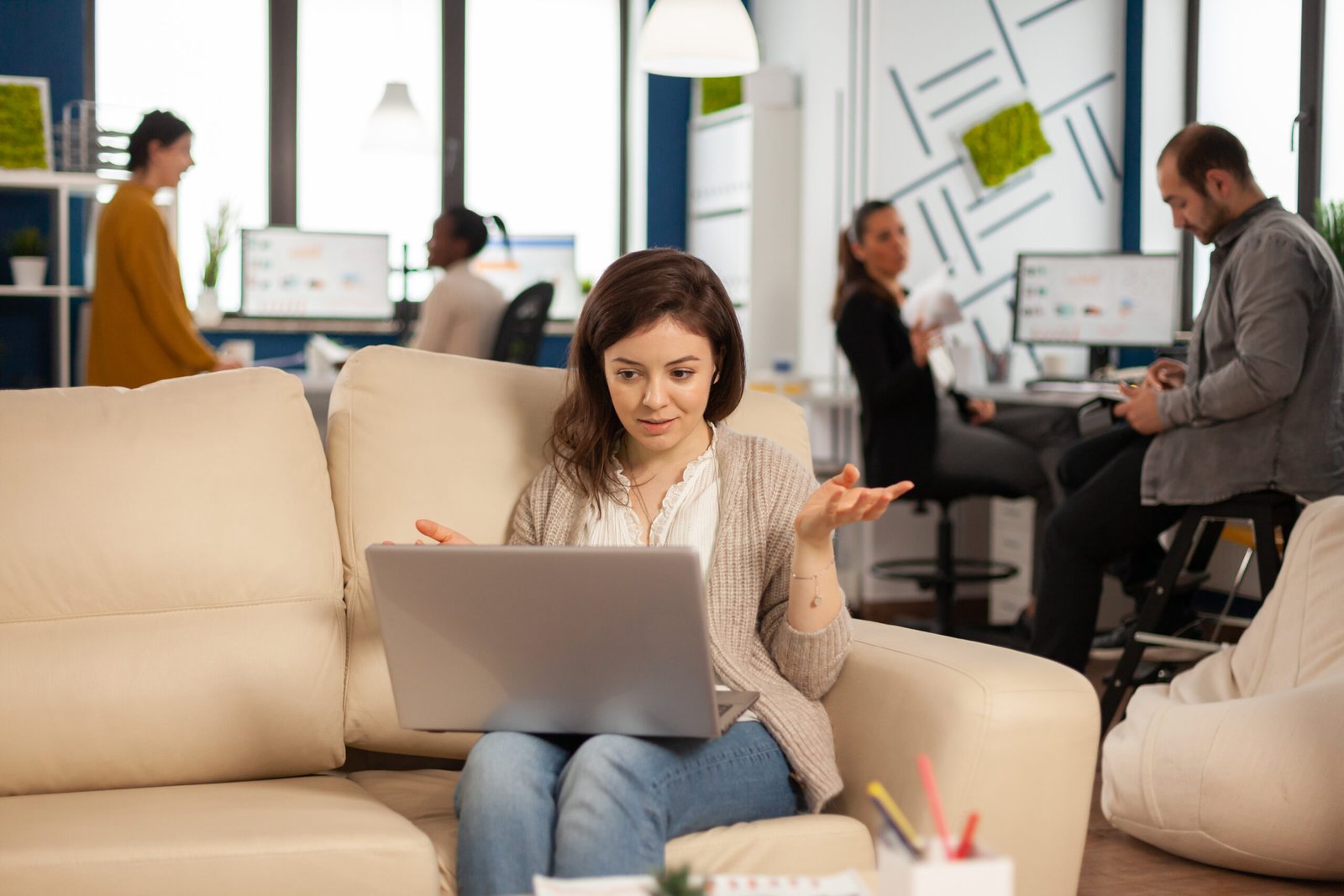 Manager woman sitting on couch holding laptop and talking on video call